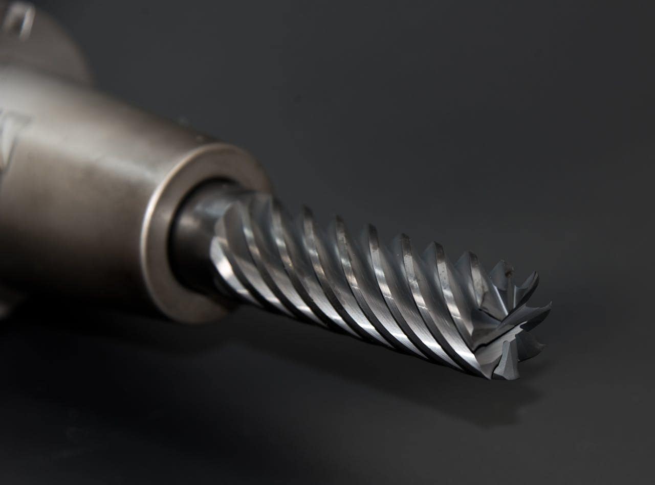 about-02 High-quality close-up of a spiral drill bit showcasing metal textures on a black background.