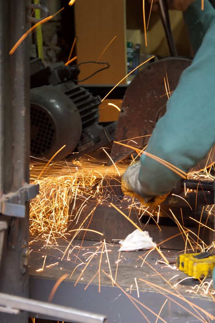our-services-1 A worker using a grinder tool with metal sparks flying in an industrial setting.
